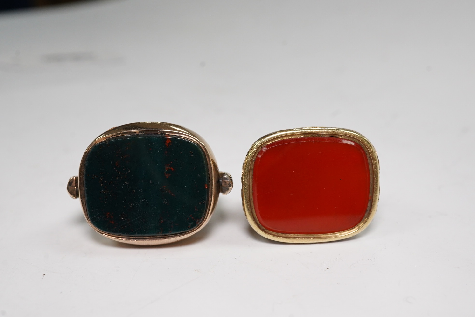 An early 20th century gold, carnelian and bloodstone set spinning fob, 34mm and one other gilt metal and carnelian set fob. Condition - poor to fair
